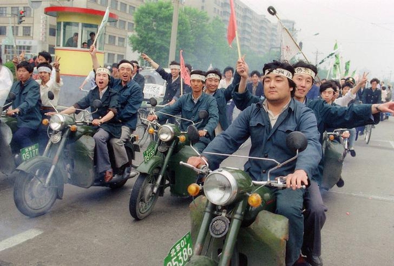 Tiananmen Square protests 19890518 - a group of workers ride motorcycles and wave flags in support of student hunger strikers